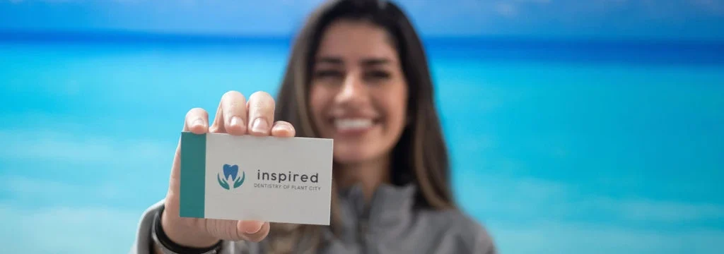 Woman holding an Inspired Dentistry of Plant City business card